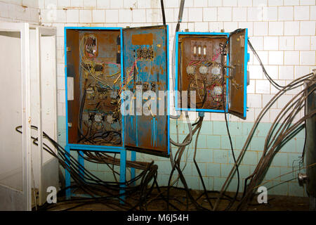 Alte zerlegt und rostige Schalttafel Montage auf einer verlassenen und zerstörten Fabrik vor dem Hintergrund des Chaos. Zerstörung und Vandalismus. Ukrai Stockfoto
