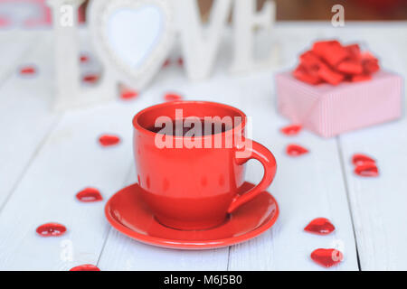 Tasse Kaffee und Geschenk im verschwommenen Hintergrund. Stockfoto