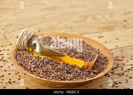 Ansicht von oben closeup Bild Leinsamen und Leinöl in einer Glasflasche auf einem hölzernen Hintergrund, geringe Tiefenschärfe. Ernährung und Nahrung für Yo Stockfoto