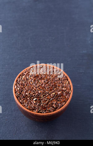 Narural raw Leinsamen in einem keramischen Ton Schüssel auf dunklem Hintergrund isoliert, close-up. Nützlich und Ernährung Ölsaaten für das tägliche Kochen. Gesunde eati Stockfoto