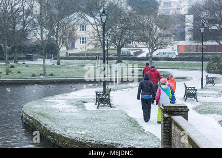 Eine Familie tragen bunte Kleidung während einer Snow Fall in Trenance Gärten in Newquay Cornwall. Stockfoto