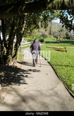 Ein Mann mit einem Fuß auf einem Pfad in Trenance Gärten in Newquay Cornwall. Stockfoto