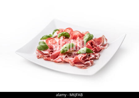 Prosciutto. Gerollte Scheiben köstliche italienische Prosciutto mit Basilikum. Stockfoto