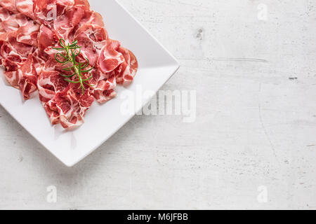 Prosciutto. Gerollte Scheiben köstliche italienische Prosciutto mit Rosmarin. Stockfoto