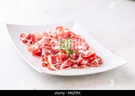 Prosciutto. Gerollte Scheiben köstliche italienische Prosciutto mit Rosmarin. Stockfoto