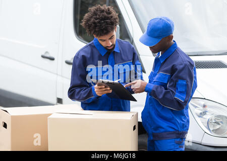 Delivery Man Schreiben auf die Zwischenablage über die Kartons durch das Fahrzeug Stockfoto