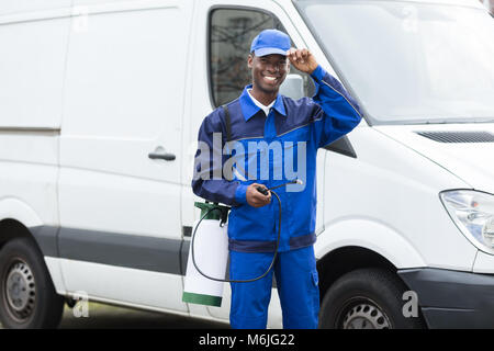 Portrait der junge lächelnde Arbeiter mit Pestizid Feldspritze Stehend von Van Stockfoto