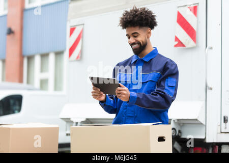 Lächelnd Lieferung Mann stand in der Nähe des Van Kontrolle seine Bestellung auf digitalen Tablet Stockfoto