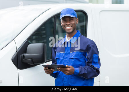 Portrait der junge lächelnde Afrikanischen Lieferung Mann von Van Holding Digital Tablet Stockfoto