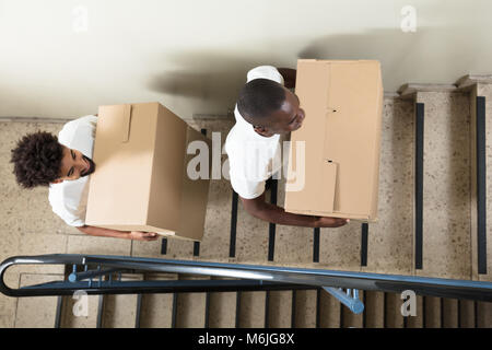 Porträt von zwei junge lächelnde Movers stehend auf Treppe Holding Kartons Stockfoto