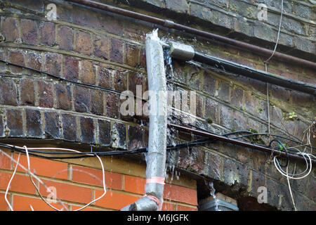 Eine undichte Wasserleitung, die ein Leck in der tauwetterperiode nach in Tagen von Frost mit Schnee und Temperaturen unter Null einfrieren entsprungen ist. UK. Stockfoto