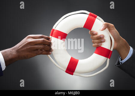 Businesspeople Holding A Lifebuoy In Hands On Gray Background Stockfoto