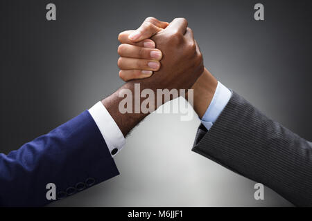 In der Nähe von zwei Unternehmer konkurrieren in den Arm Wrestling auf grauem Hintergrund Stockfoto