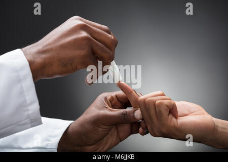 Close-up von Ärzten mit Lancet am Finger Blutzuckerspiegel kontrollieren Stockfoto