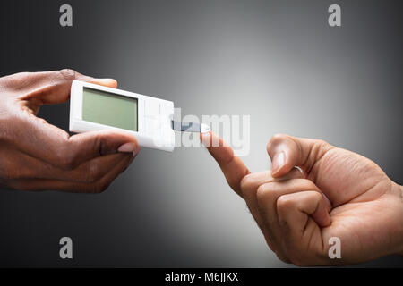 Close-up von Ärzten mit Glucometer am Finger Blutzuckerspiegel kontrollieren Stockfoto