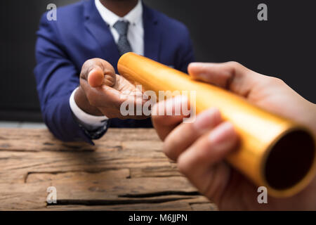 In der Nähe von einem Geschäftsmann Hand vorbei an goldenen Staffelstab an seinen Partner Stockfoto