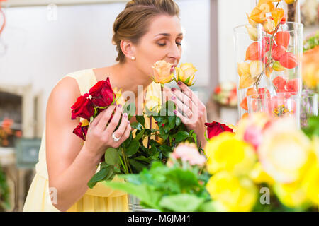 Floristin Frau riecht an Rosen Stockfoto