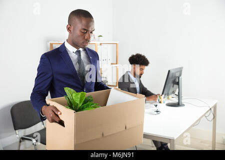 Unternehmer, die mit Karton aus dem Amt mit den Arbeiten am Schreibtisch Stockfoto