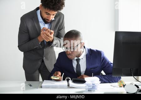 Besorgt man sich an junge Prüfer Analyse Bill am Arbeitsplatz suchen Stockfoto