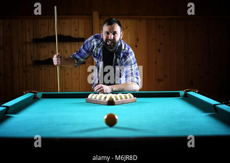 Ein Mann mit einem Bart spielt eine große Billard. Partei in einem 12-Fuß-Pool Stockfoto