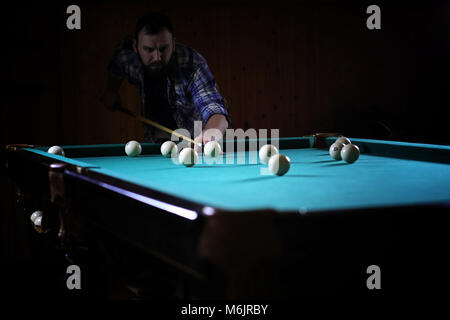 Ein Mann mit einem Bart spielt eine große Billard. Partei in einem 12-Fuß-Pool Stockfoto