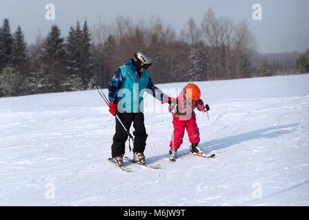 PERM, Russland - 24. FEBRUAR 2018: Mann lehrt ein Kind Skifahren auf einem schneebedeckten Berg Stockfoto