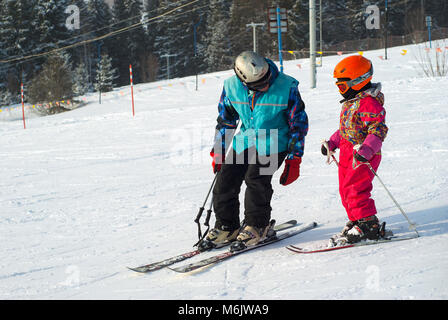 PERM, Russland - 24. FEBRUAR 2018: Mann lehrt ein Kind Skifahren auf einem schneebedeckten Berg Stockfoto