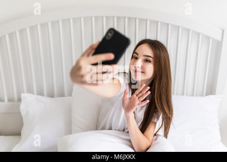 Schöne Mädchen, das Selfie im Bett Stockfoto