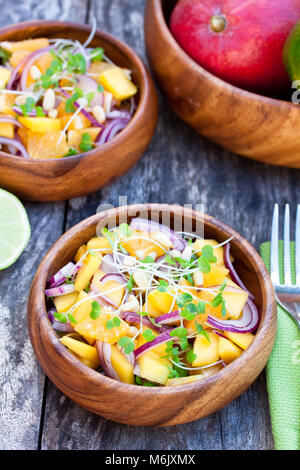 Vegetarische Salat mit Mango orangen und roten Zwiebeln in den hölzernen Platte Stockfoto