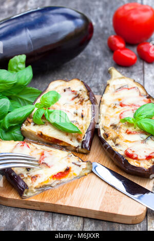 Gebacken, gefüllt mit Käse und Tomaten auf dem hölzernen Tisch Aubergine Stockfoto