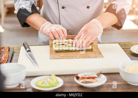 Kochen Hände machen japanische Sushi rollen. Stockfoto