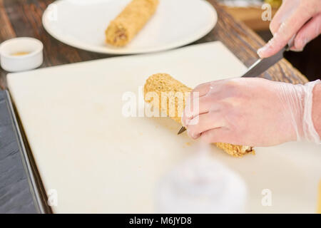 Koch Hände mit Messer schneiden von Sushi rollen. Stockfoto