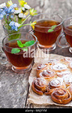 Hausgemachte Zimtkuchen mit Teetassen und Bündel von wilden Blumen Stockfoto