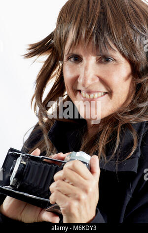 Attraktive Frau mittleren Alters mit braunen layered Hair und lächelnd, während Sie einen antiken Kamera isoliert auf weißem Stockfoto