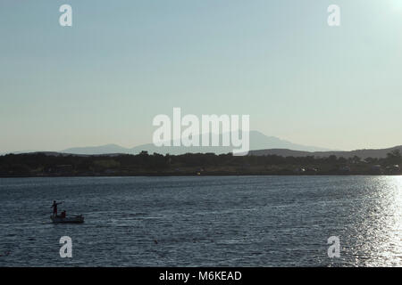 Blick auf ein kleines Fischerboot mit hintergrundbeleuchteter, ruhige Ägäische Meer und Landschaft in Cunda (alibey) Insel. Stockfoto