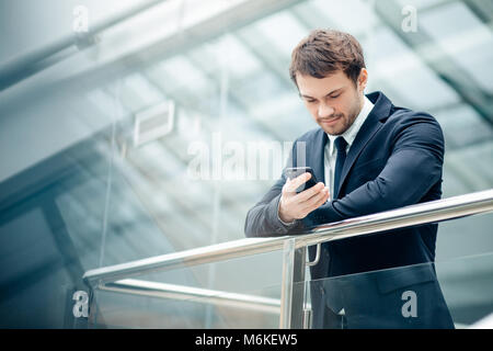 Geschäftsmann mit Smartphone über Bürogebäude Stockfoto