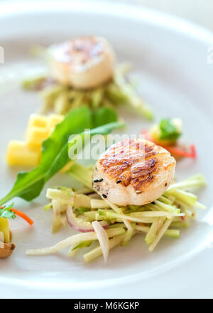 Gebratene Hokkaido scallopes mit würzigen Mango Salat auf weiße Platte Stockfoto