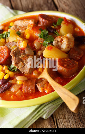 Nationale Küche von Kap Verde: Cachupa mit Fleisch, Chorizo und Gemüse close-up auf einem Teller auf dem Tisch. Vertikale Stockfoto