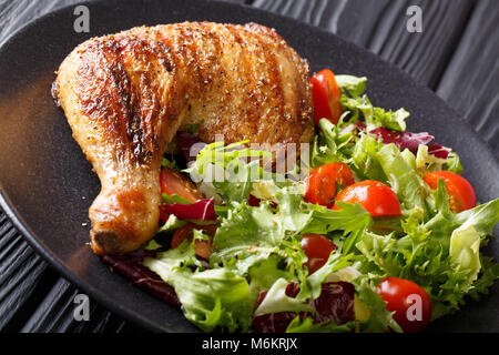 Fried Chicken Bein mit frischem Gemüse Salat close-up auf einem Teller auf dem Tisch. Horizontale Stockfoto