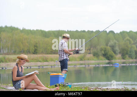 junges Paar Angeln am Ufer des Teiches Stockfoto