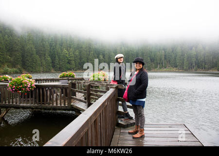 Asain Thai Frauen Mutter und Tochter reisen und im Waterfront Holzbrücke posiert am Mummelsee See bei Regen im Schwarzwald, Schwarzwald B Stockfoto