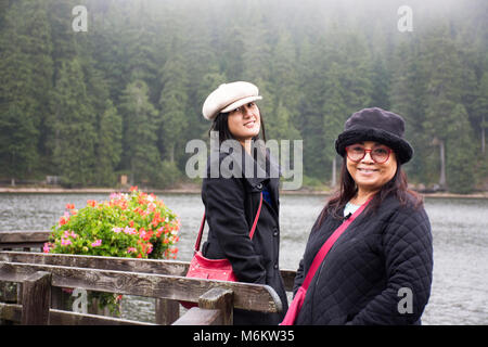 Asain Thai Frauen Mutter und Tochter reisen und im Waterfront Holzbrücke posiert am Mummelsee See bei Regen im Schwarzwald, Schwarzwald B Stockfoto