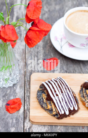 Tasse Kaffee mit Mohn Brötchen glasiert mit Schokolade und Mohn Blumen Stockfoto