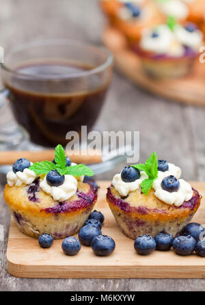 Frische Muffins mit Heidelbeeren und Tasse Kaffee auf Holz- Hintergrund Stockfoto