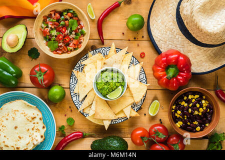 Traditionelle mexikanische Nahrung auf Holztisch. Tortilla Chips, Guacamole, Nachos, Bohnen und Salsa. Tabelle Ansicht von oben Stockfoto