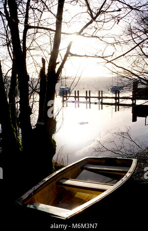 Lake Windermere, Lake District, Großbritannien, ein Ruderboot auf der Küstenlinie mit einem Holzsteg, am frühen Morgen Blick über die flache ruhigen See bildet eine complet Stockfoto