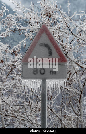 Schild Gefahr Kurve in Eis nach dem Regen abgedeckt Stockfoto