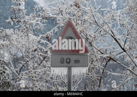 Schild Gefahr Kurve in Eis nach dem Regen abgedeckt Stockfoto