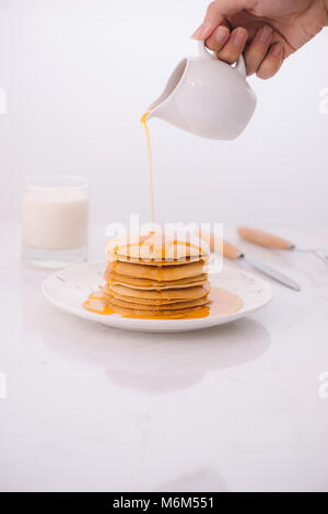 Pfannkuchen zum Frühstück mit Honig und Milch. Stockfoto