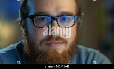 Nahaufnahme von einem jungen Bartgeier kreativen Mann mit Brille sieht lächelnd in die Kamera. Stockfoto